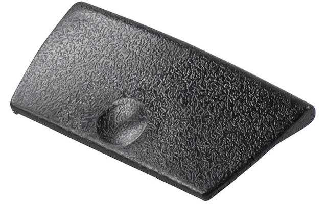 Pièce en plastique noire en forme trapézoïdale, surface texturée et petite dépression ronde