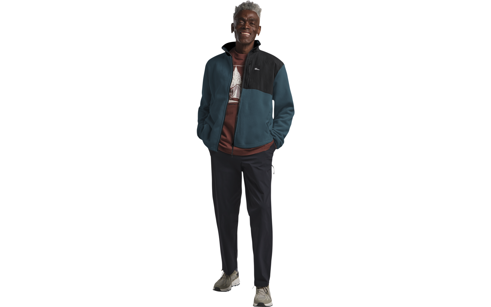 Älterer Mann mit grauem Haar trägt eine blaue Jacke und schwarze Hose, steht vor weißem Hintergrund