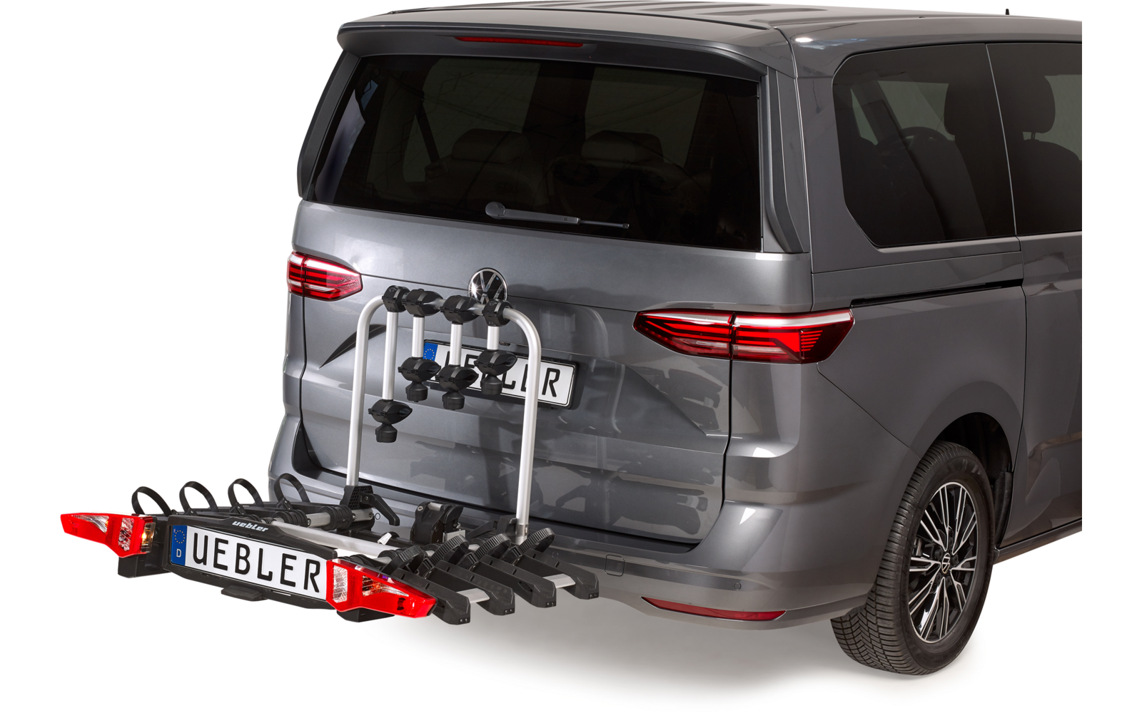 Heck eines grauen Vans mit an der Anhängerkupplung montiertem Fahrradträger mit mehreren Halterungen und Kennzeichen 'UEBLER'