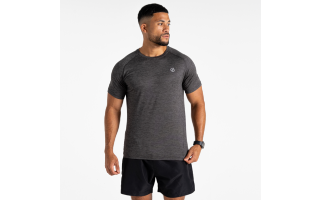 Homme debout devant un fond blanc, portant un t‑shirt gris foncé à manches courtes avec petit logo sur la poitrine, un short noir et une montre connectée au poignet gauche, regardant sur le côté