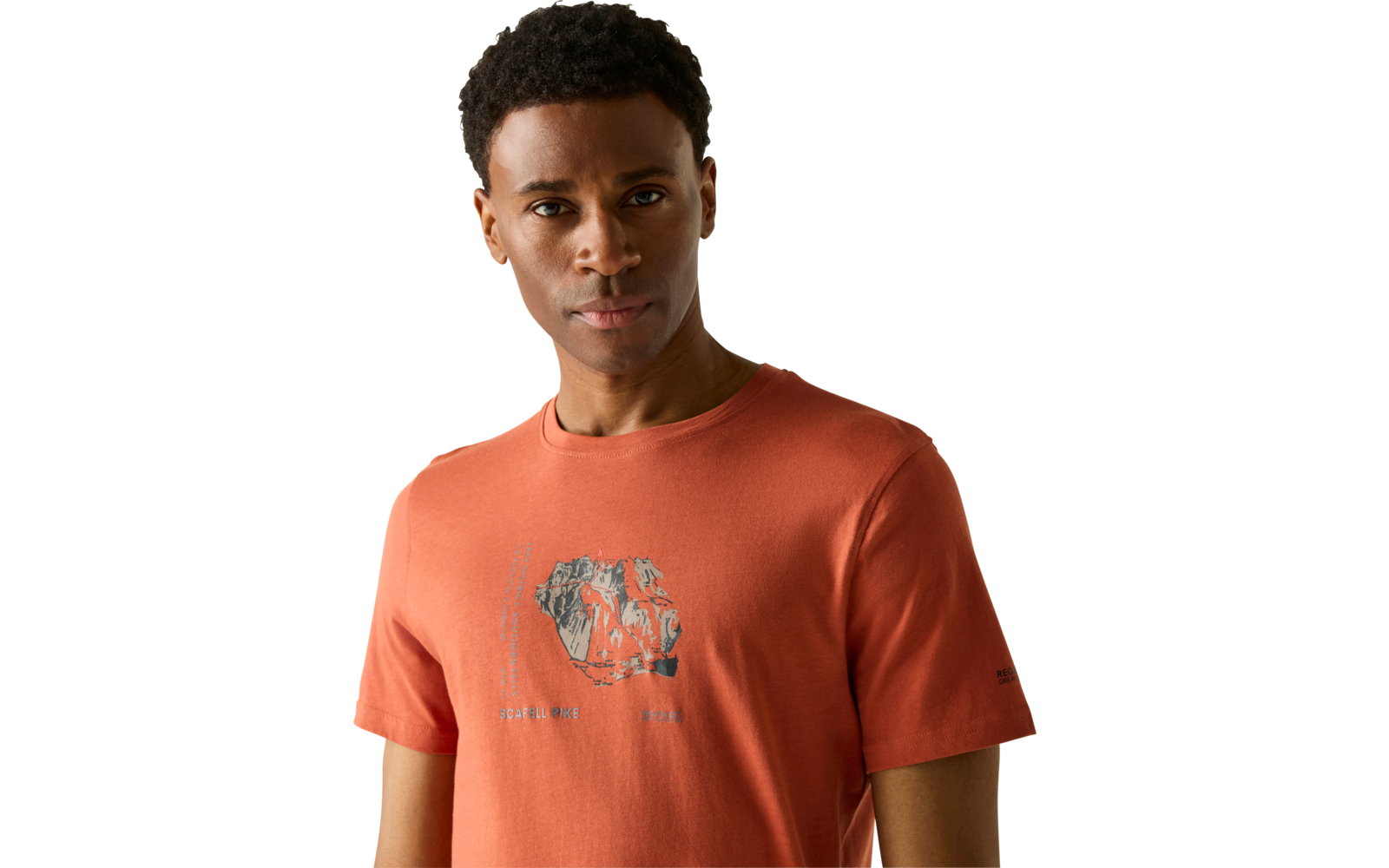 Porträt eines Mannes, Brustanschnitt, trägt orangefarbenes T‑Shirt mit kleiner zentrierter Grafik, heller einfarbiger Hintergrund