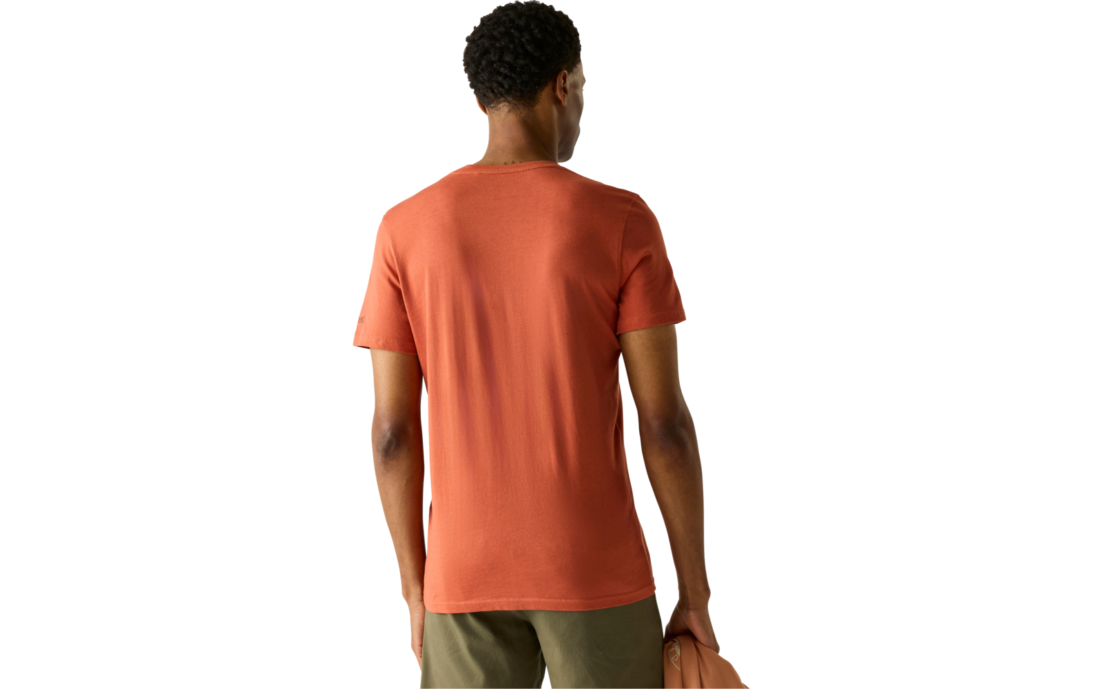 Rückansicht einer Person mit kurzem dunklem Haar, orangefarbenem T‑Shirt, olivgrünen Hosen und einer orangefarbenen Tasche in der rechten Hand