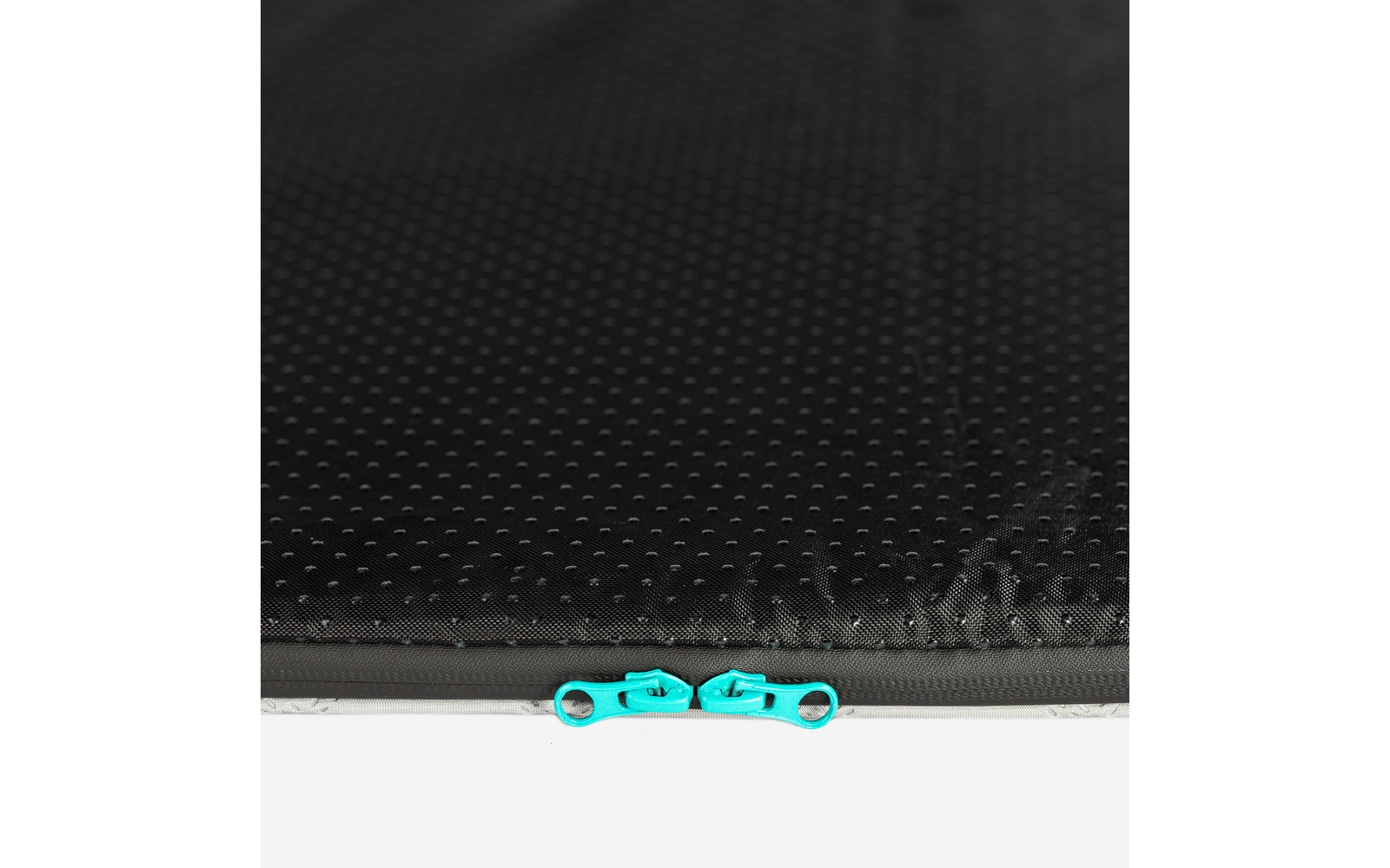 Schwarze, genoppte Oberfläche mit zwei türkisfarbenen Zipper-Schiebern nebeneinander an der unteren Kante; darunter silberner Rand und weißer Hintergrund
