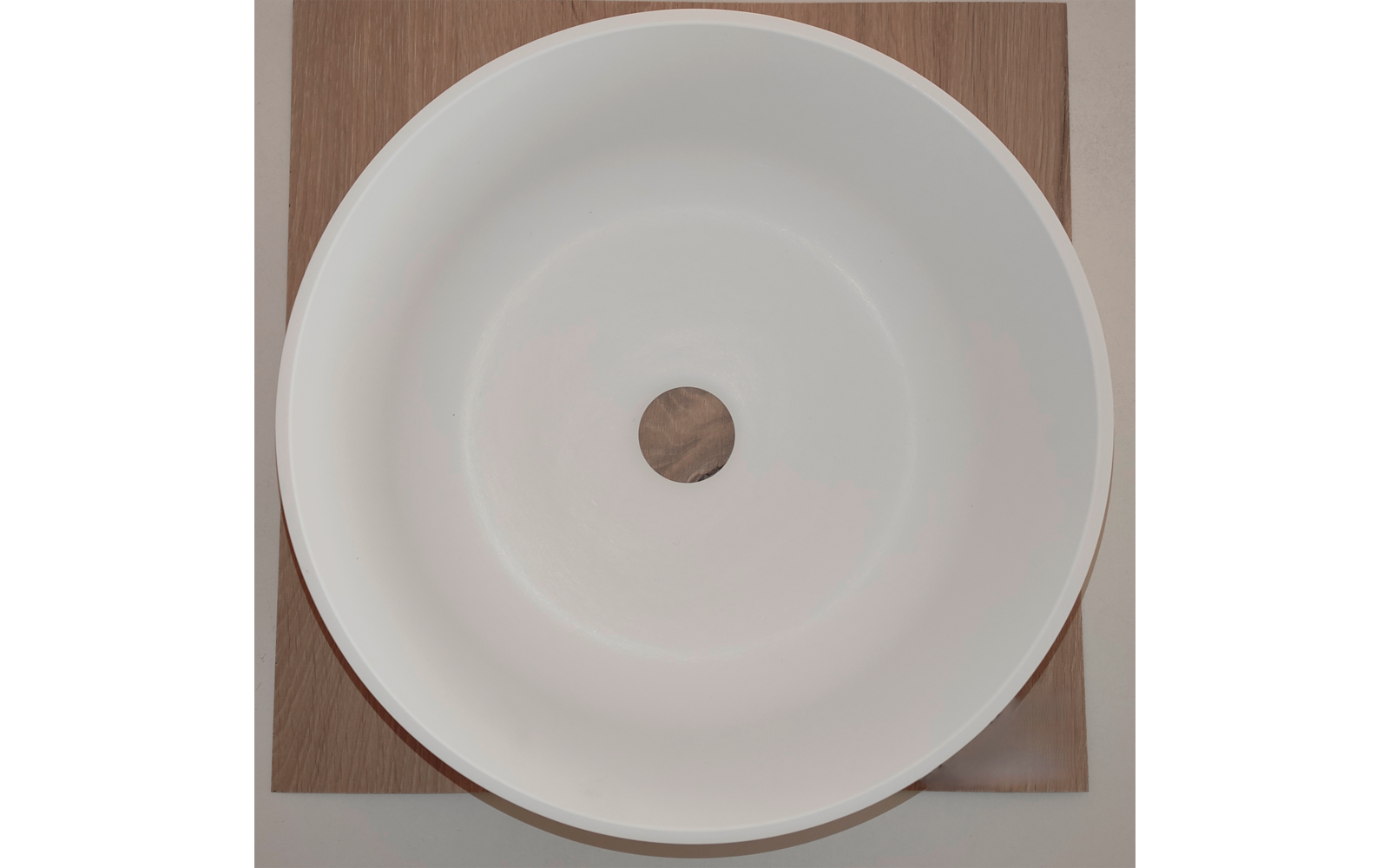 Witte ronde kom met een centraal rond gat op een vierkante houten plank, bovenaanzicht