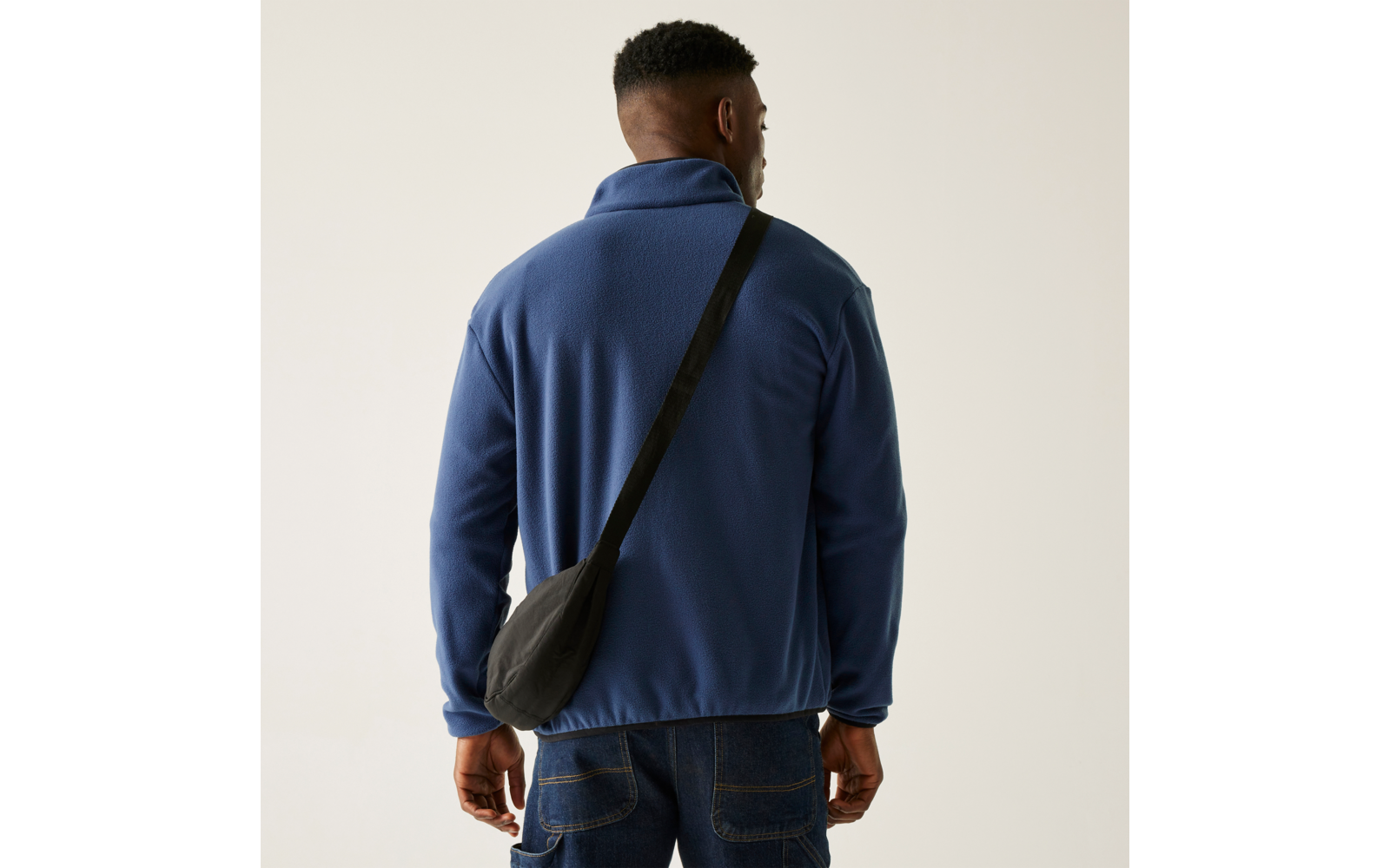 Mann von hinten in blauem Pullover mit Umhängetasche