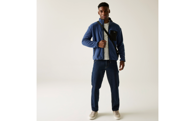 Mann trägt blaue Jacke und blaue Hose vor weißem Hintergrund
