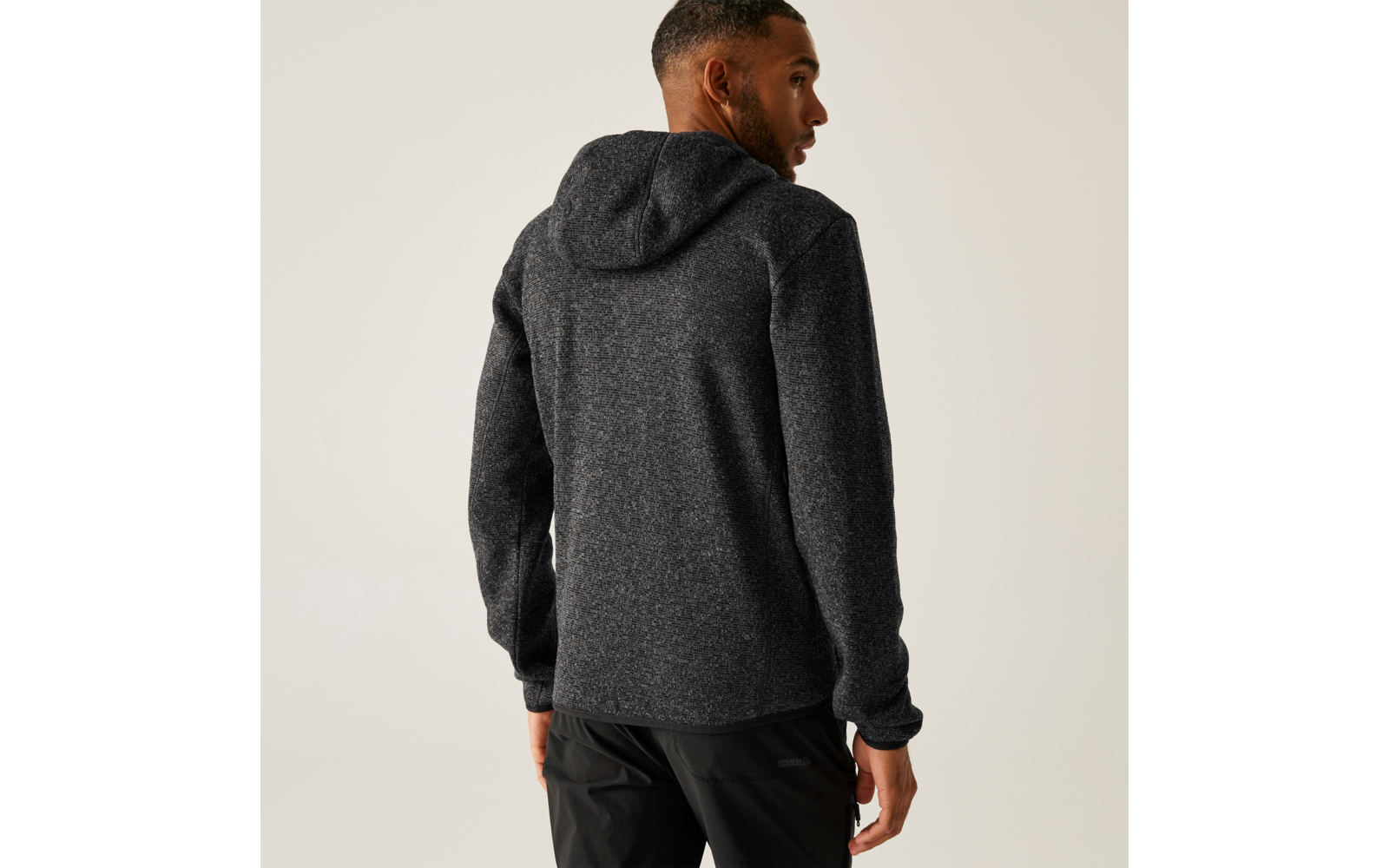 Ein Mann trägt einen dunklen Kapuzenpullover und steht mit dem Rücken zur Kamera