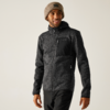 Personne portant un bonnet beige en maille, une veste polaire gris foncé à fermeture éclair avec panneau noir sur la poitrine et poche poitrine zippée, pantalon noir, debout devant un fond clair et regardant vers la droite