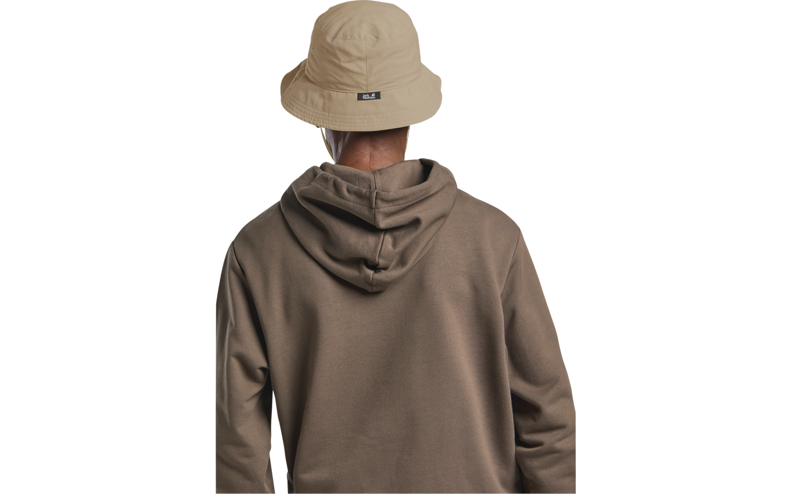 Person von hinten, trägt beige Anglerhut mit schwarzem Etikett auf der Rückseite und braunen Kapuzenpullover
