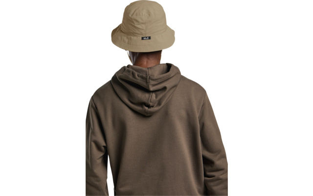 Person von hinten, trägt beige Anglerhut mit schwarzem Etikett auf der Rückseite und braunen Kapuzenpullover