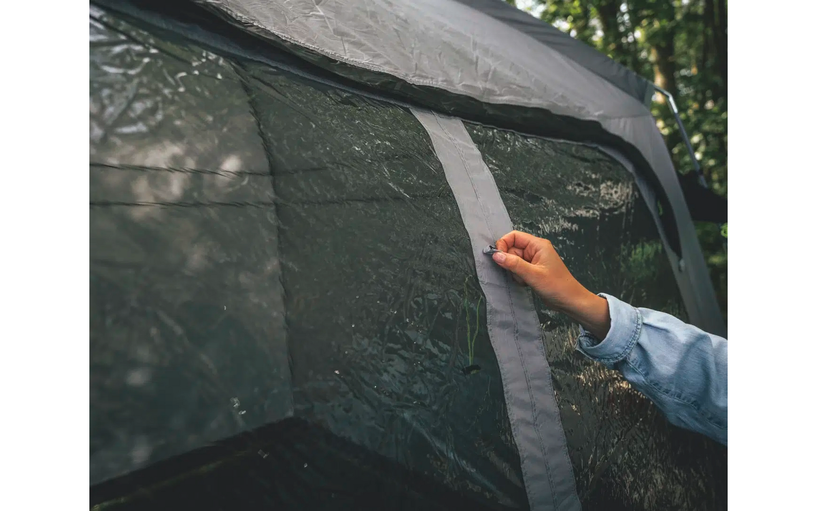 Main fermant une fermeture éclair sur une tente grise