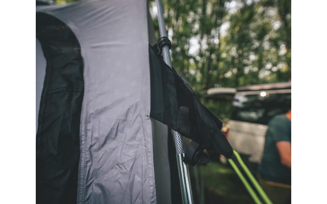 Poteau de tente avec gant noir fixé, voiture et arbres flous en arrière-plan