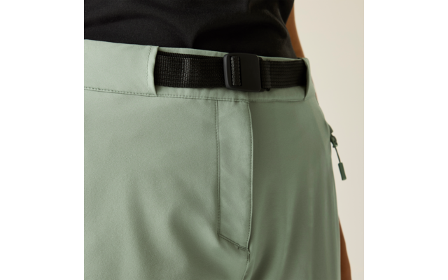 Close-up van een taille met lichtgroene broek, zwarte stoffen riem met gesp en een zijritssluiting