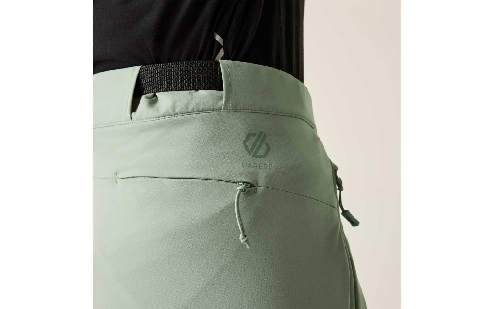 Heupgebied van een persoon met lichtgroene broek, zijritszak met koord, zichtbaar logo DARE2B op de broek, zwart bovenstuk en zichtbare zwarte riem