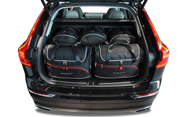 Coffre ouvert d'une voiture noire avec cinq sacs noirs à liserés rouges