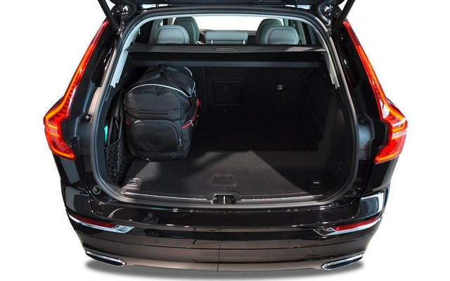 Coffre ouvert d'une voiture noire avec un sac à dos noir à gauche, sièges arrière visibles et plancher de chargement recouvert de moquette