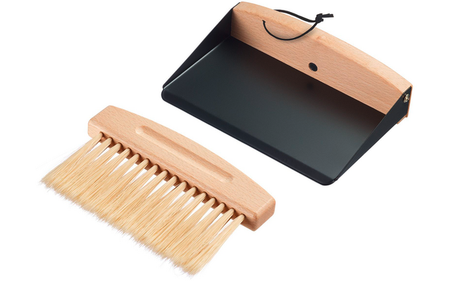 Small wooden hand brush with light bristles next to a black dustpan with wooden handle and hanging loop