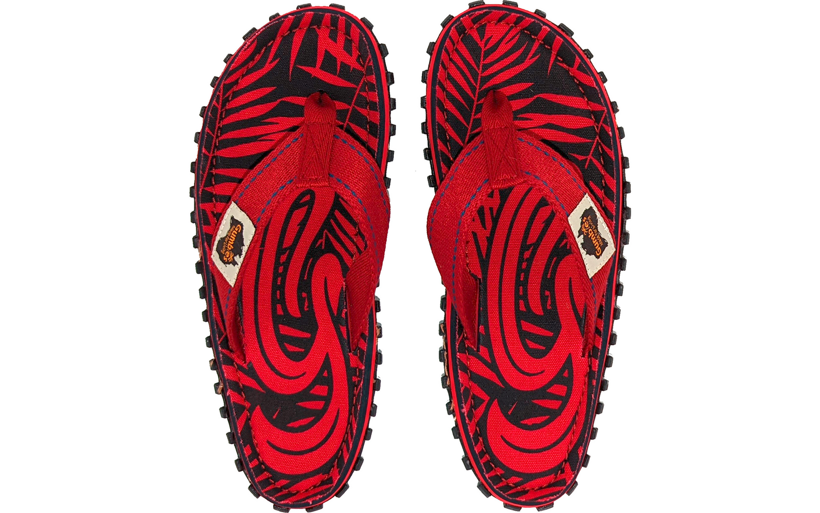 Paar rote Flip-Flops von oben, schwarzes Muster, schwarze profilierte Sohlen, rote Stoffriemen mit kleinem beigen Aufnäher