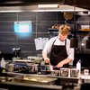 Ein Koch arbeitet in einer Restaurantküche mit schwarzen Fliesenwand