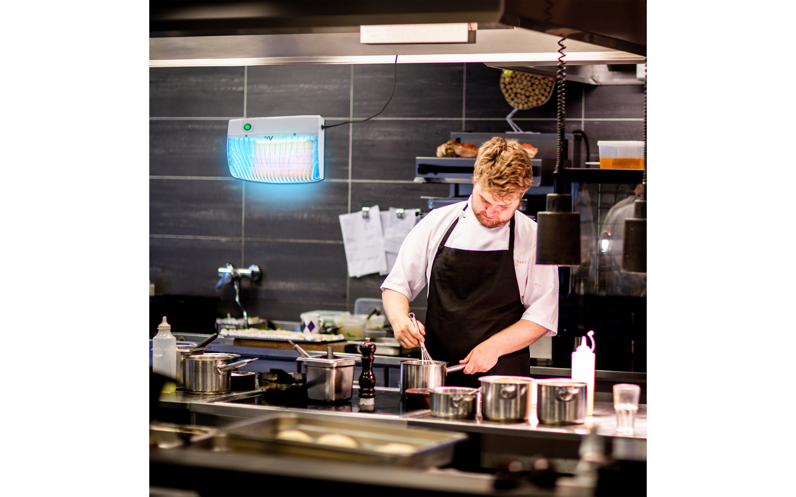 Ein Koch arbeitet in einer Restaurantküche mit schwarzen Fliesenwand
