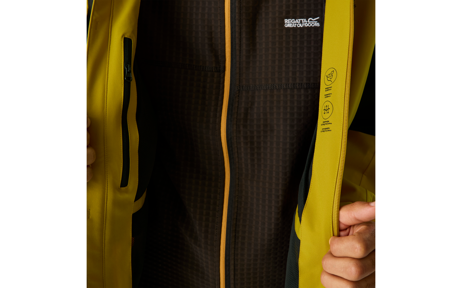 Nahaufnahme einer geöffneten gelben Jacke mit dunklem Innenfutter, orangefarbener Reißverschlusskante, sichtbarem Schriftzug 'Regatta Great Outdoors' und zwei Händen, die die Jacke halten