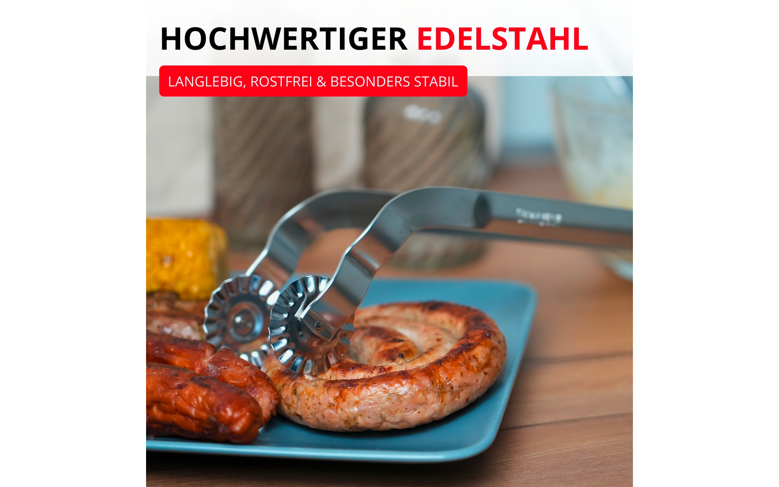 Pince en acier inoxydable tenant une saucisse enroulée sur une assiette bleue; autres saucisses et un morceau d’épi de maïs sur une table en bois; bannières promotionnelles allemandes visibles en haut