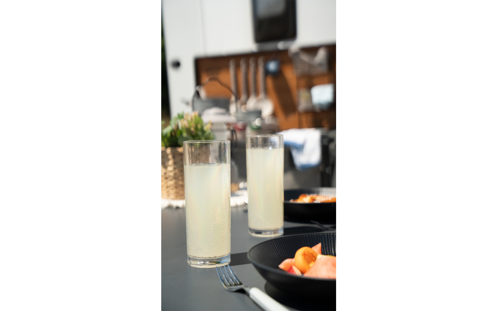 Twee glazen met een lichtgekleurde drank op een tafel, een wazige zithoek op de achtergrond