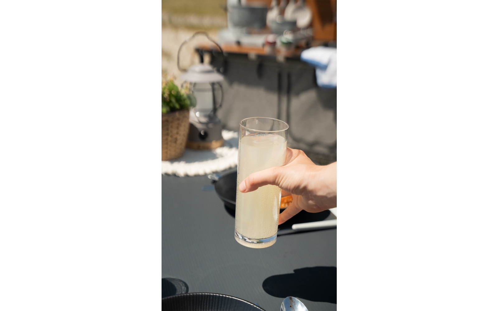 Hand houdt een glas melk vast in een buitenomgeving