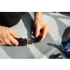 Dos manos sostienen piezas de conector de plástico negro sobre una superficie gris texturizada; varios conectores, incluido un anillo azul, están a su lado