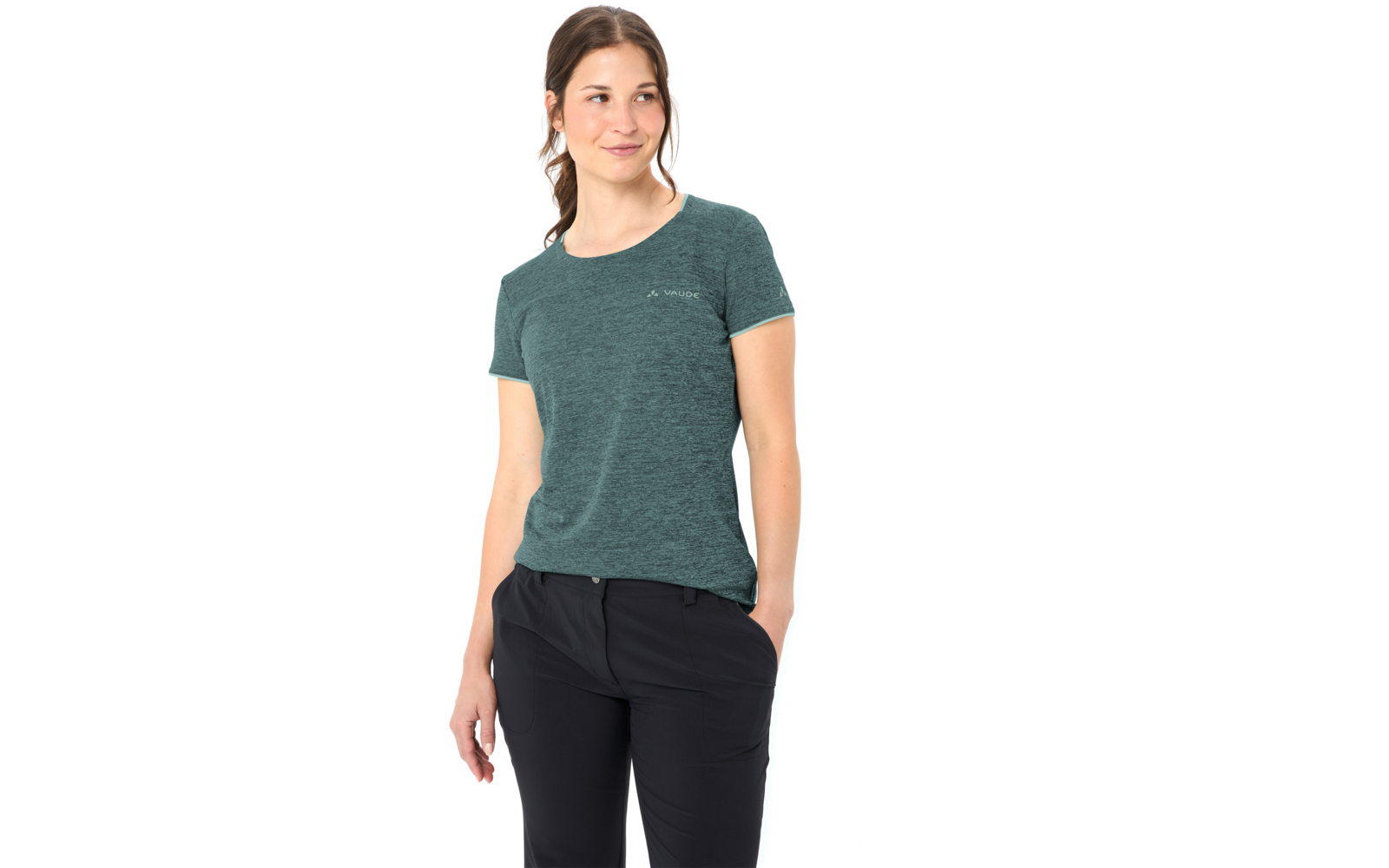 Person mit gebundenem Zopf, türkisgrünes kurzärmeliges T-Shirt mit kleinem Logo, schwarze Hose, seitlich stehend, Blick nach rechts, weißer Hintergrund