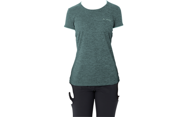 Persona in piedi di fronte alla fotocamera, indossa una maglietta verde e pantaloni neri