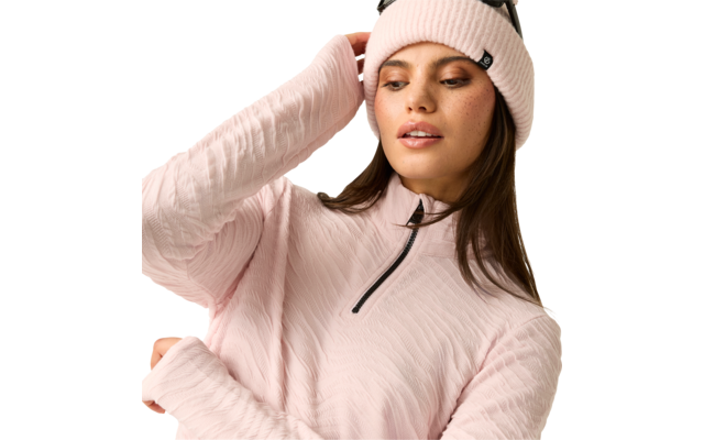 Person mit rosa Strickmütze, rosa wattiertem Pullover mit kurzem Reißverschluss, Sonnenbrille auf der Mütze, Blick nach unten rechts