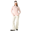 Person mit rosa Strickmütze und Skibrille auf dem Kopf, rosa Fleecepullover mit kurzem Reißverschluss, weiße Skihose und schwarze Stiefel, stehend und frontal