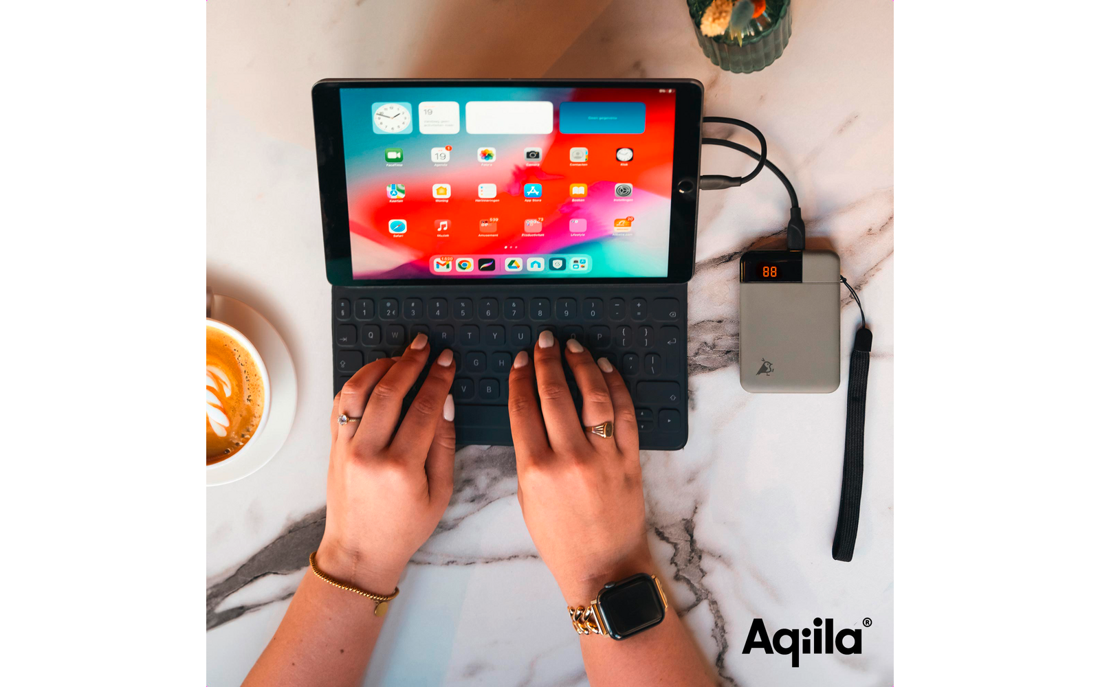 Handen typen op een zwart laptops toetsenbord met een kleurrijk scherm, naast een kopje koffie en een externe harde schijf aangesloten