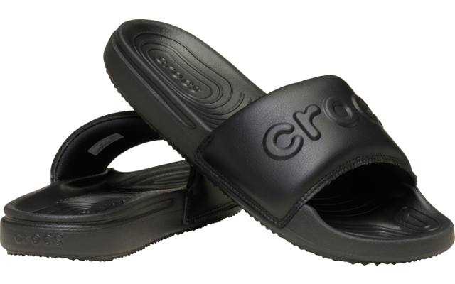 Zwei schwarze Slide-Sandalen, eine liegt teilweise auf der anderen; „crocs“ auf dem oberen Riemen geprägt