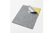 Grijs rechthoekig viltvel met een opgekrulde hoek, waarbij een zilverkleurige laag en een gele laag eronder zichtbaar zijn op een witte achtergrond