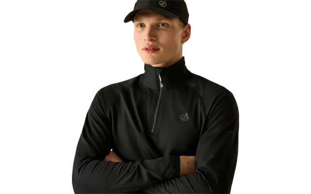 Homme avec casquette noire et pull noir à demi-fermeture éclair, bras croisés, regarde vers la droite