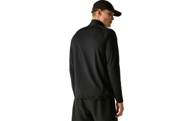 Personne vue de dos, porte une casquette noire, un haut à manches longues noir et un pantalon noir, regarde par-dessus son épaule droite