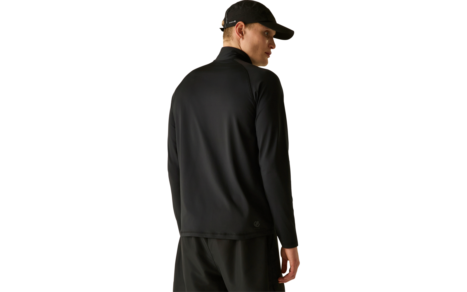 Personne vue de dos, porte une casquette noire, un haut à manches longues noir et un pantalon noir, regarde par-dessus son épaule droite