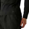 Bas du torse et main droite d'une personne, haut noir à manches longues et pantalon noir, logo blanc 'ILUS' sur l'ourlet du haut