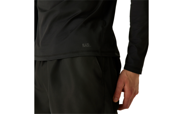 Bas du torse et main droite d'une personne, haut noir à manches longues et pantalon noir, logo blanc 'ILUS' sur l'ourlet du haut