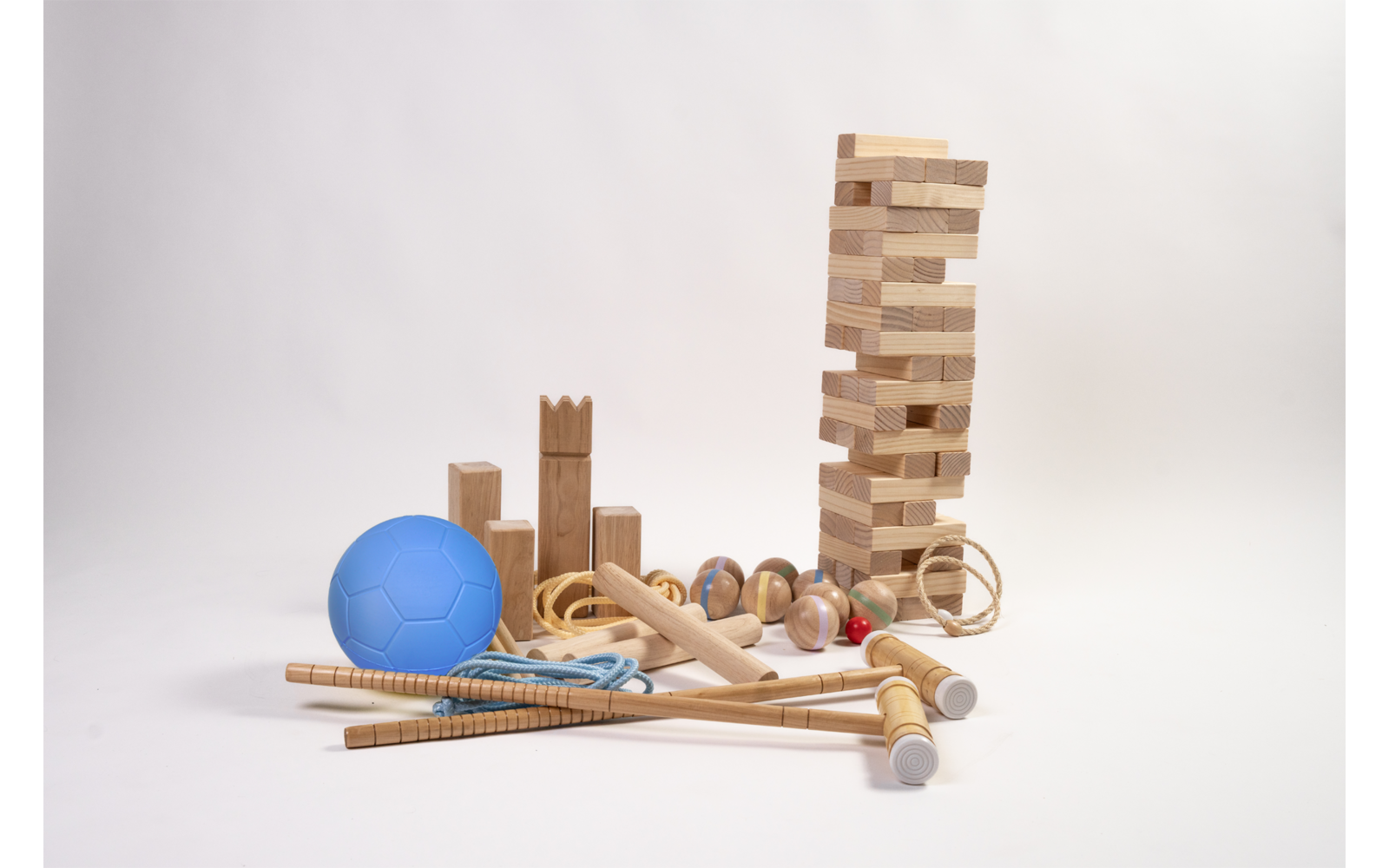 Blauwe bal, diverse houten bouwblokken en houten speelgoed, hoge toren van houten blokken, meerdere houten staven en een springtouw op witte achtergrond