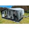 Caravan with attached awning on a grassy field under blue sky