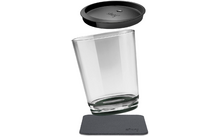 Een doorzichtig glas met een zwarte deksel en een zwarte onderzetter