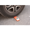Una rueda de coche está sobre un dispositivo electrónico de medición rojo en el asfalto