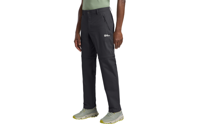 Persona con pantalones negros, camiseta verde claro y zapatos grises, sosteniendo una bolsa marrón