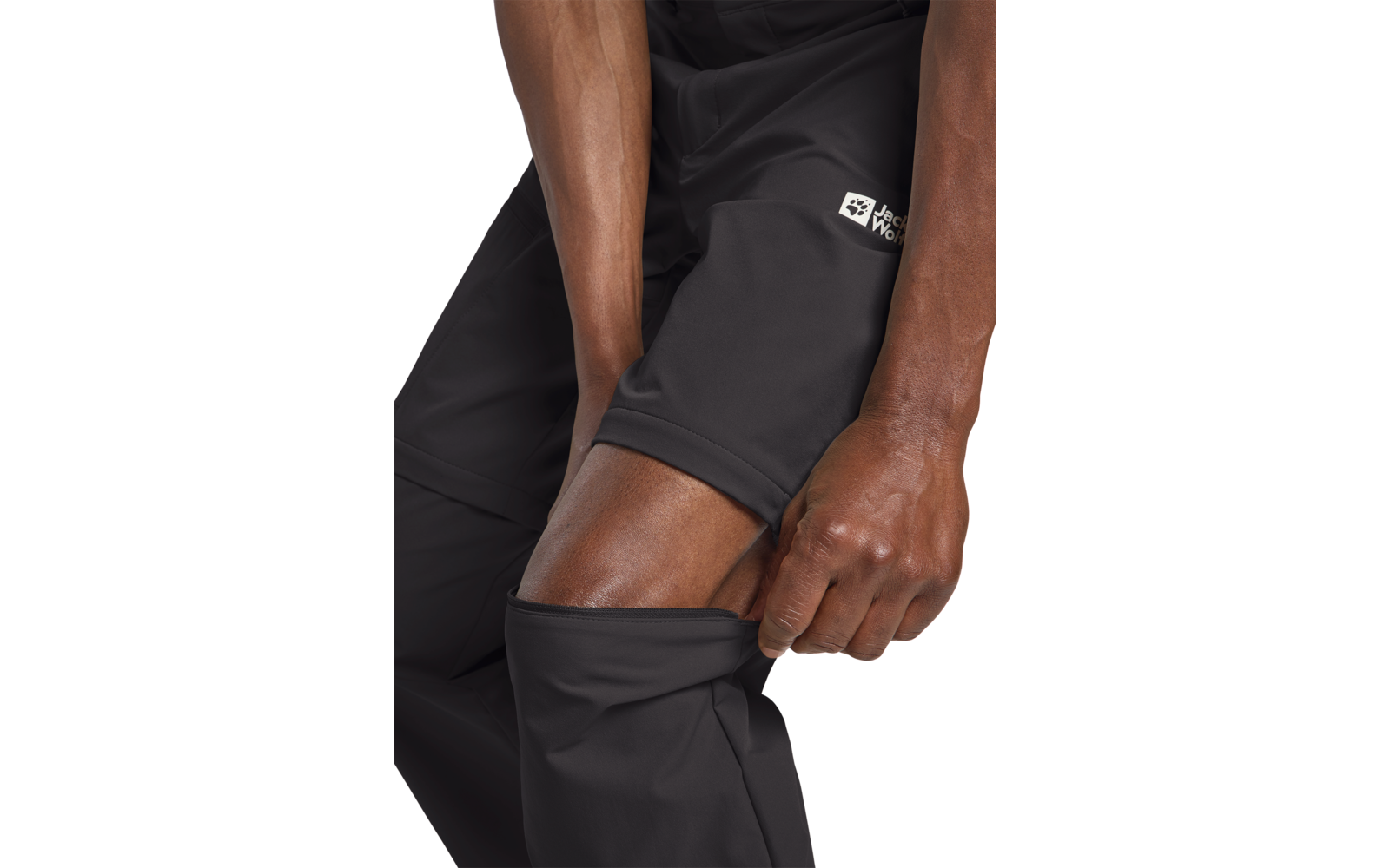 Hombre quitándose pantalones negros, mostrando leggings cortos negros de capa base