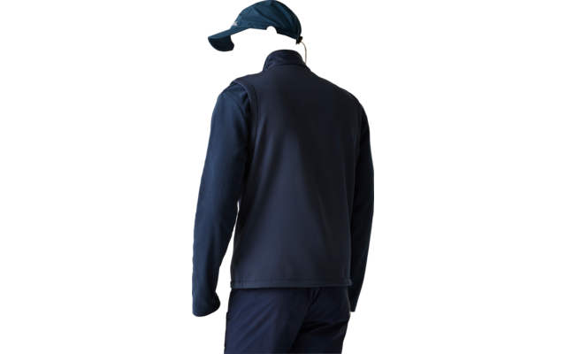 Person seen from behind wearing a navy vest over a long-sleeve shirt, navy pants and a navy baseball cap, light background