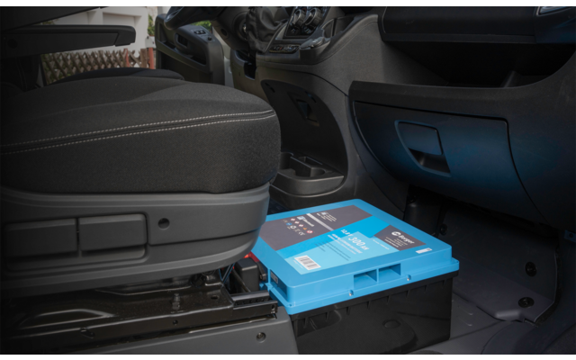 Fahrzeuginnenraum mit schwarzem Stofffahrersitz, Armaturenbrett, Boden und einem blauen Kunststoffkasten mit Aufklebern unter dem Sitz