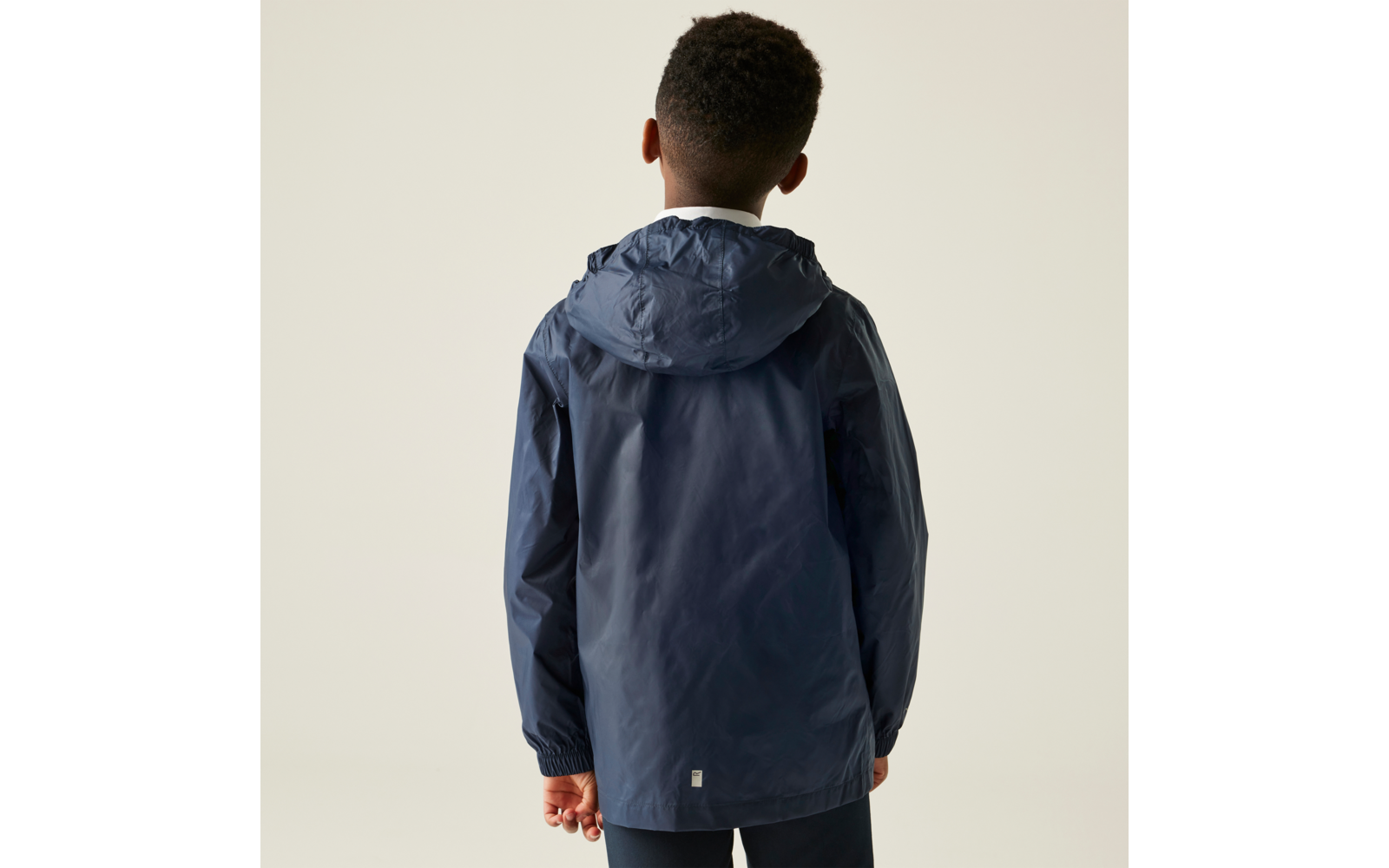 Rückansicht eines Jungen mit einer dunkelblauen Kapuzenjacke vor hellem Hintergrund